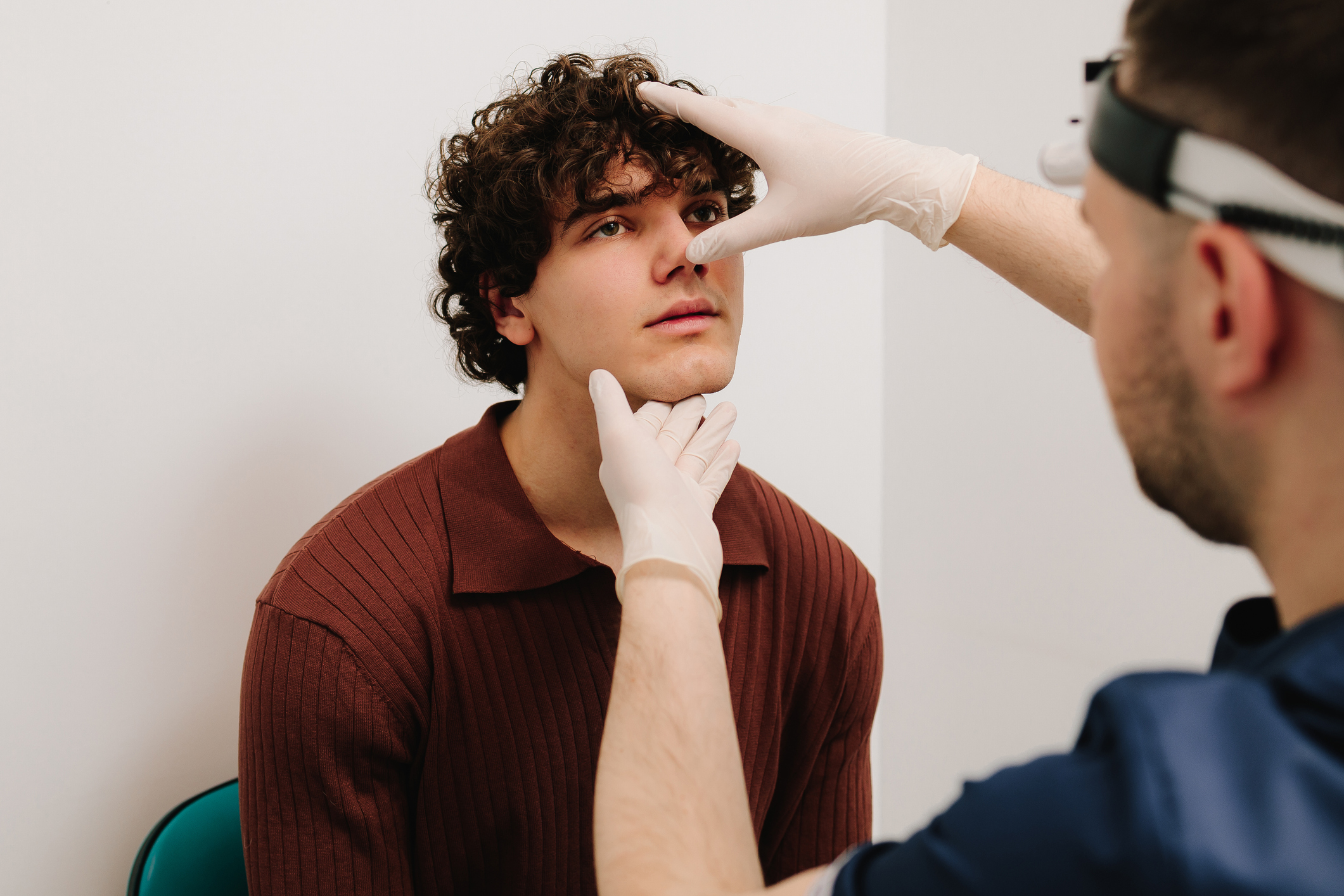 Doctor examines nose of male patient before male rhinoplasty.