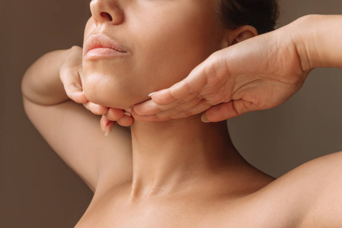 Young woman touching under the chin with hands massaging her face. Exercises from the second chin