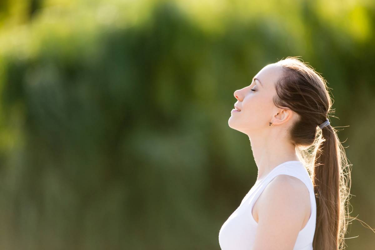 Portrait of beautiful smiling young woman enjoying yoga, relaxing, feeling alive, breathing fresh air, got freedom from work or relations, calm and dreaming with closed eyes, in green park, copy space